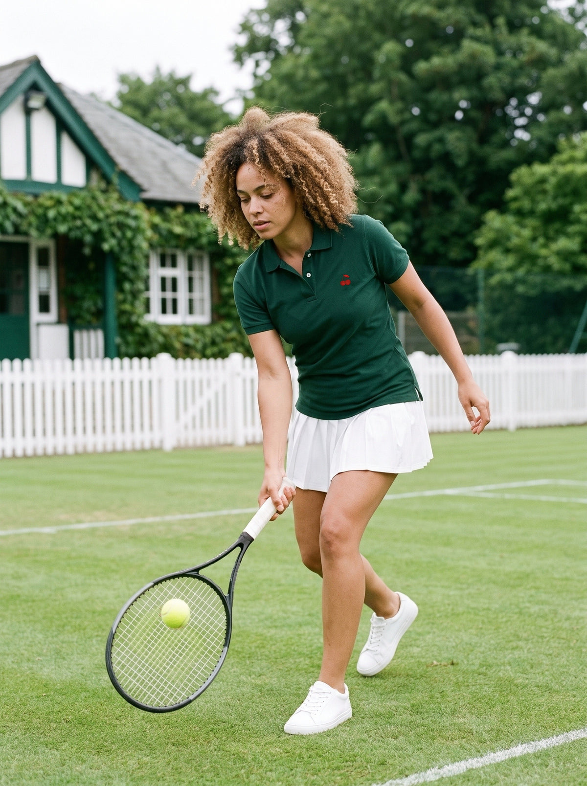 A Bottle Green club polo and a white tennis skirt on a grass court